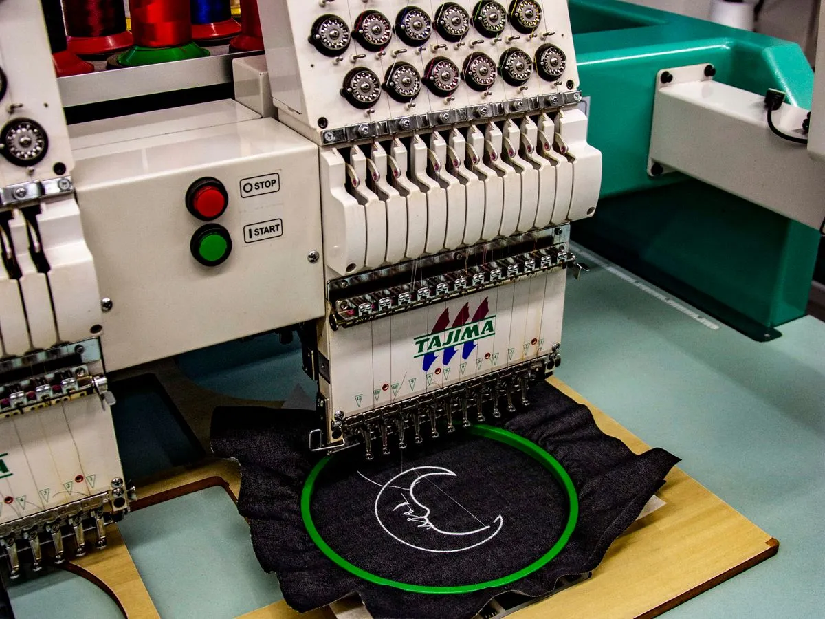 Professional embroidery machine stitching a company logo on fabric in Ajman